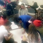 Photo of a group of college students seated on the floor and working on a map together